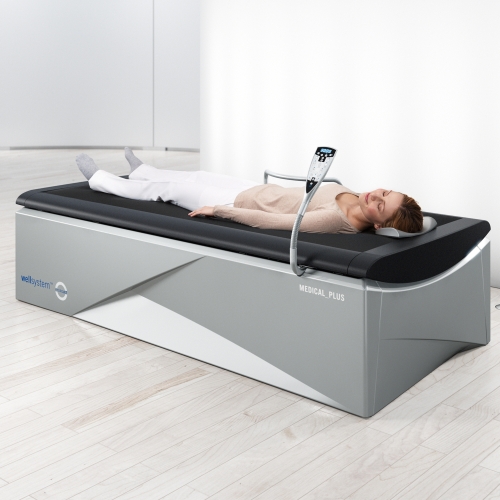 Osoba podczas zabiegu na łóżku Wellsystem Medical Plus z pilotem sterującym.